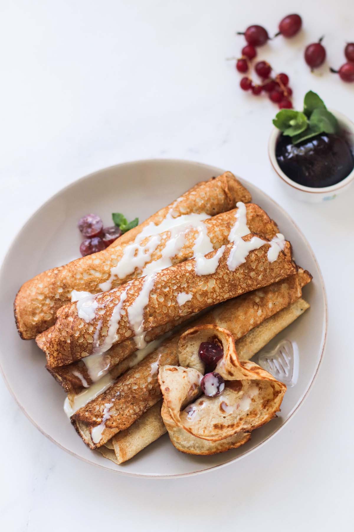 Rolled pancakes on a plate and drizzled with sauce.