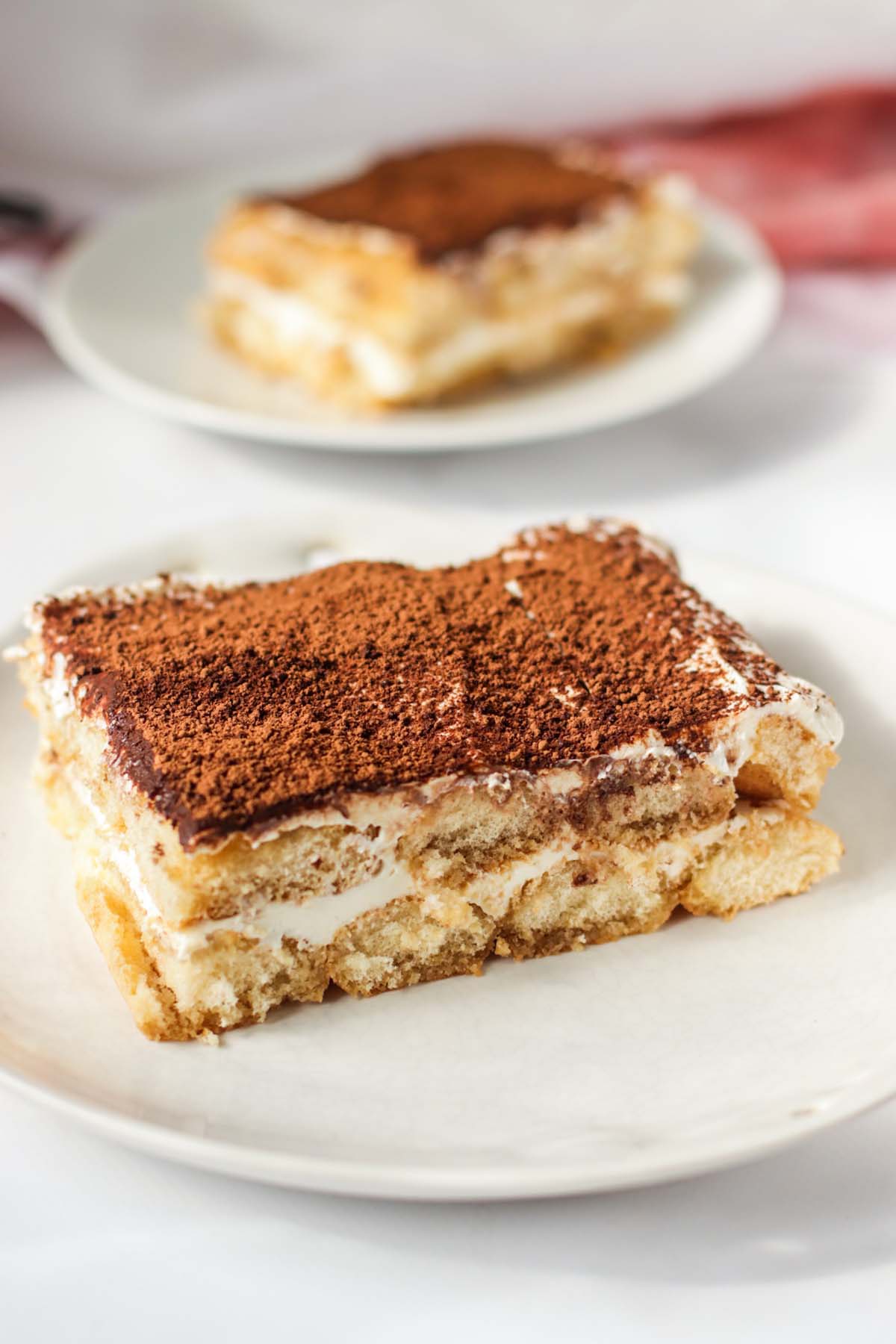 Two plates with a slice of tiramisu on each plate.