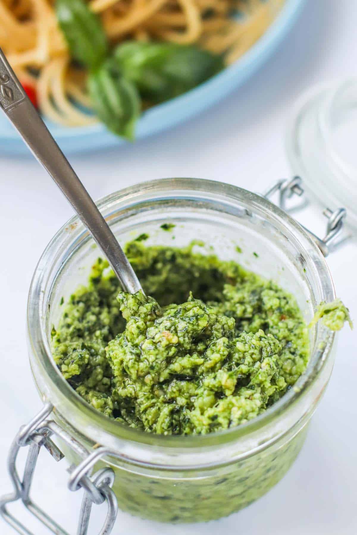 Pesto in a container with a spoon.