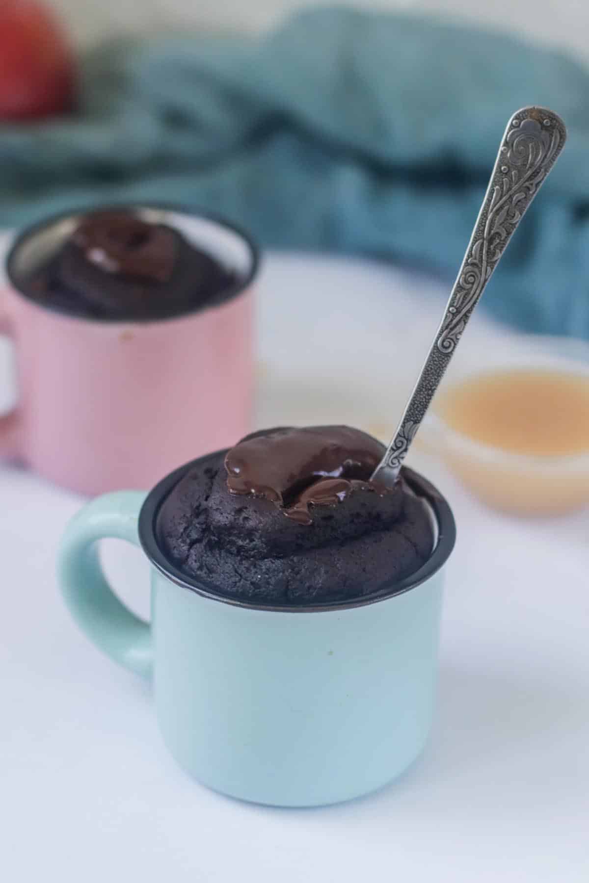 A spoon stuck in a mug with cake.