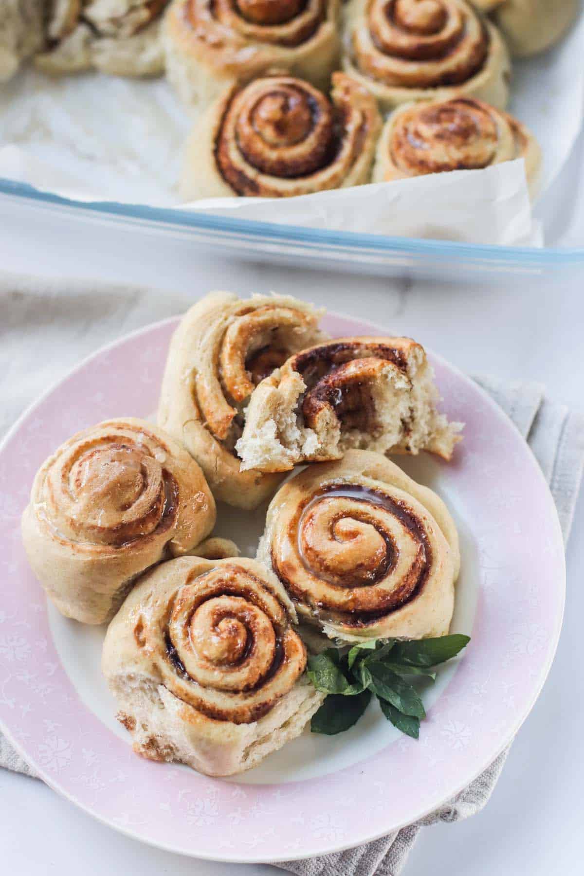 Cinnamon rolls on a plate and one is cut in half.
