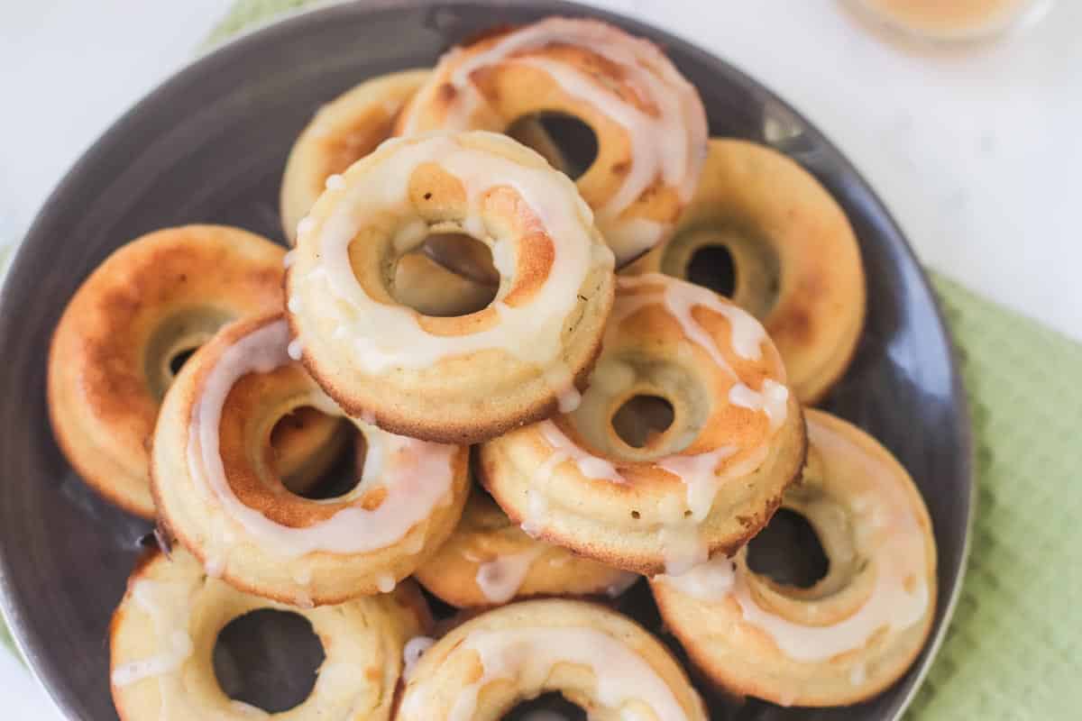 Donuts stacked on a plate and drizzled with icing.