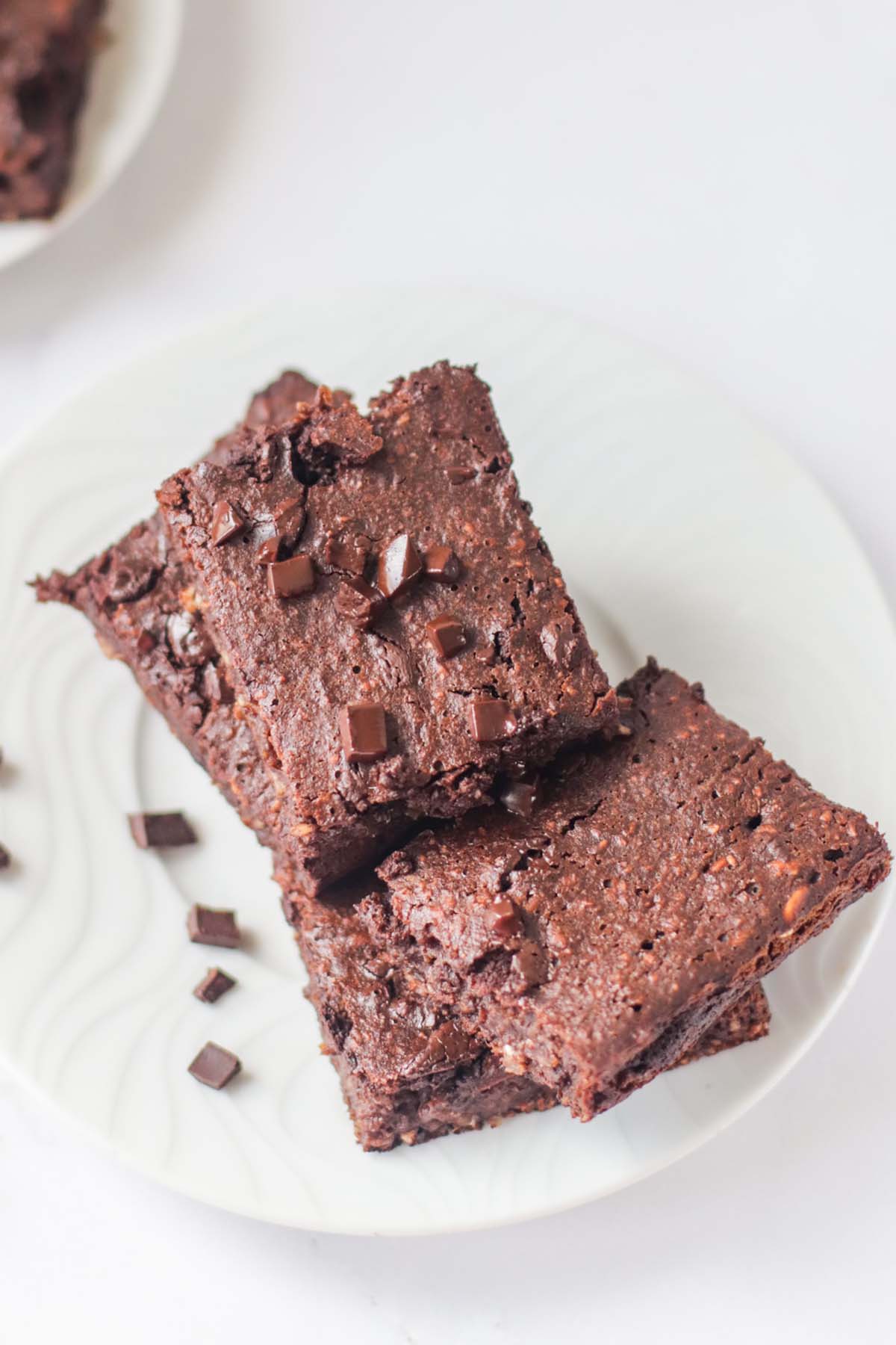 Brownies on a plate with chocolate chunks sprinkled over them.