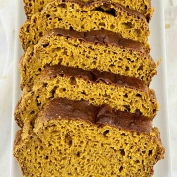 A sliced loaf of pumpkin bread on a white plate.
