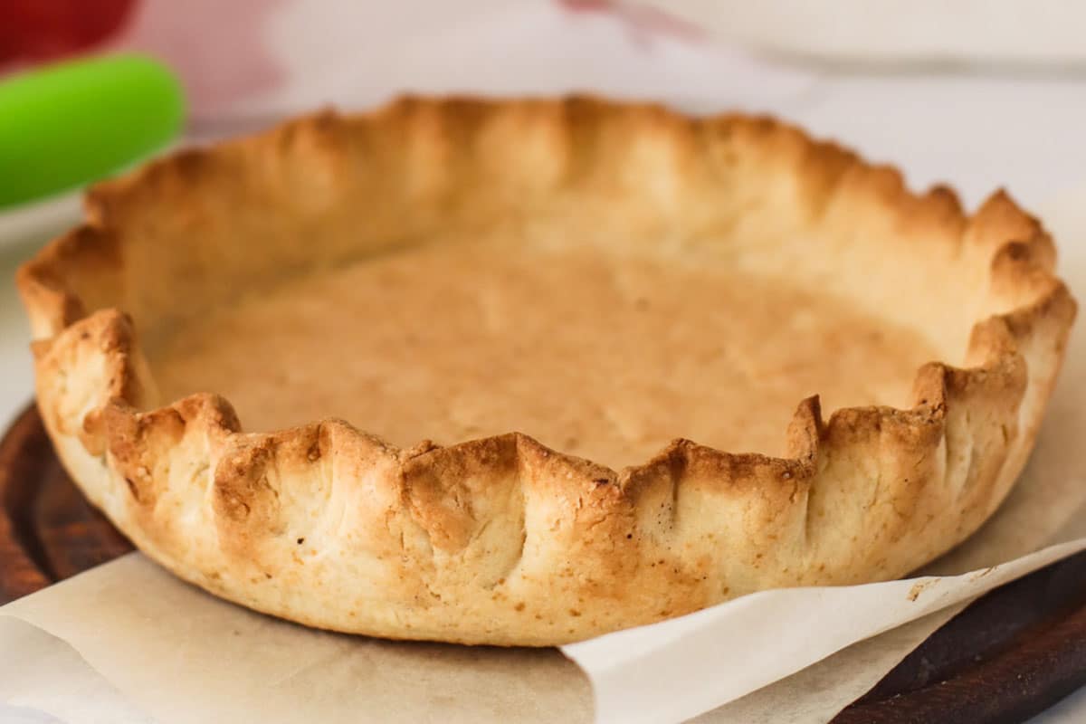 A baked pie crust on parchment paper.