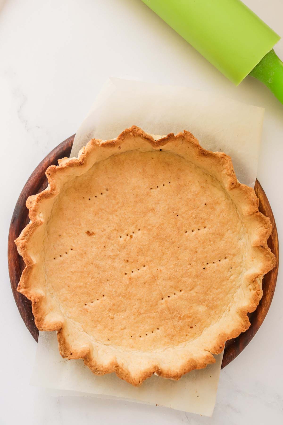 A baked crust on a table with a rolling pin.