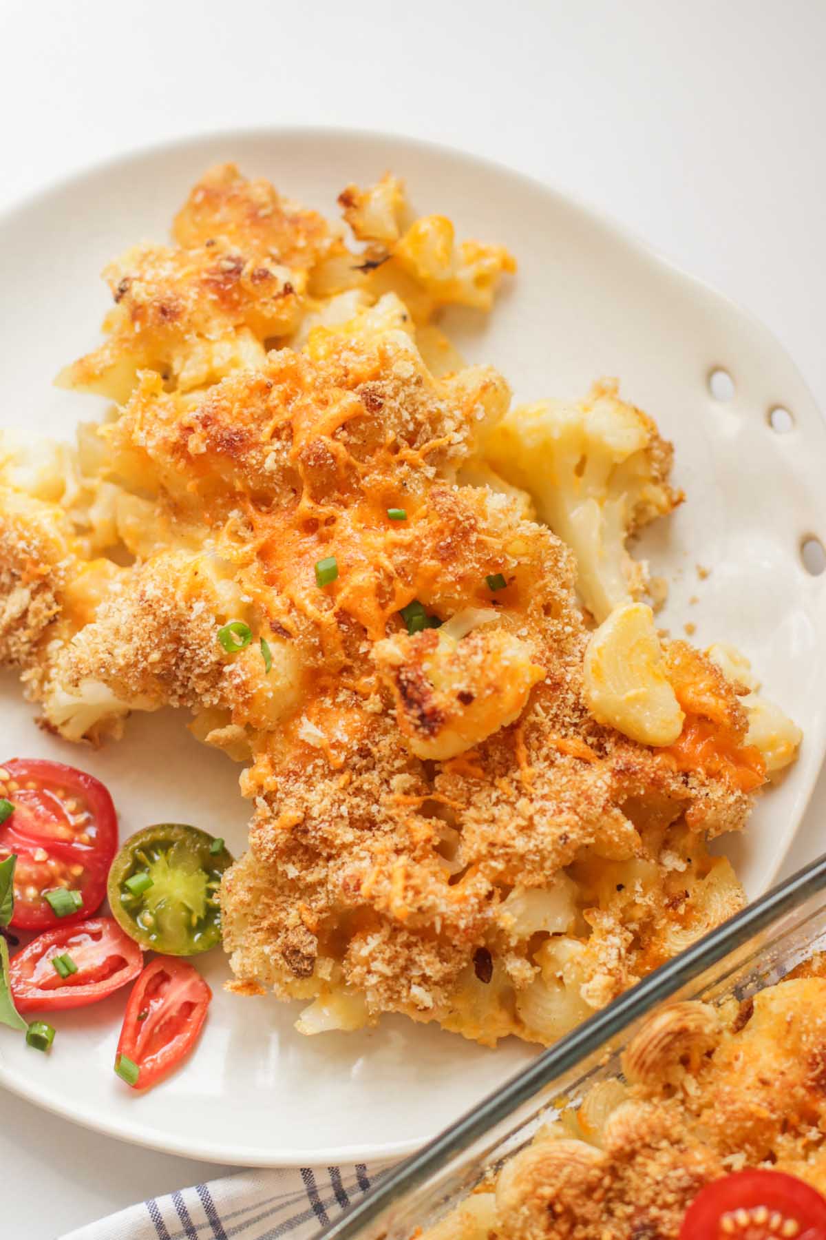 Mac and cheese on a white plate next to the baking dish.