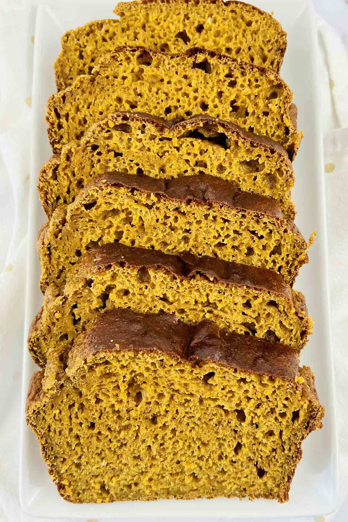 A sliced loaf of pumpkin bread on a white plate.