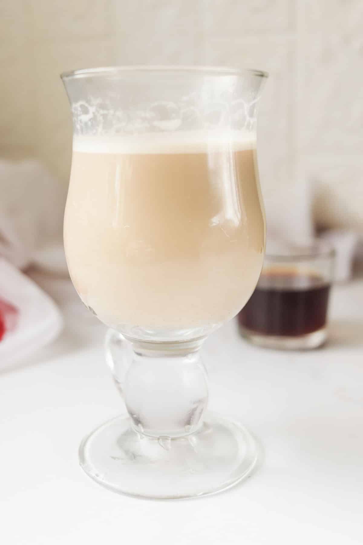 A latte in a glass on a white table.