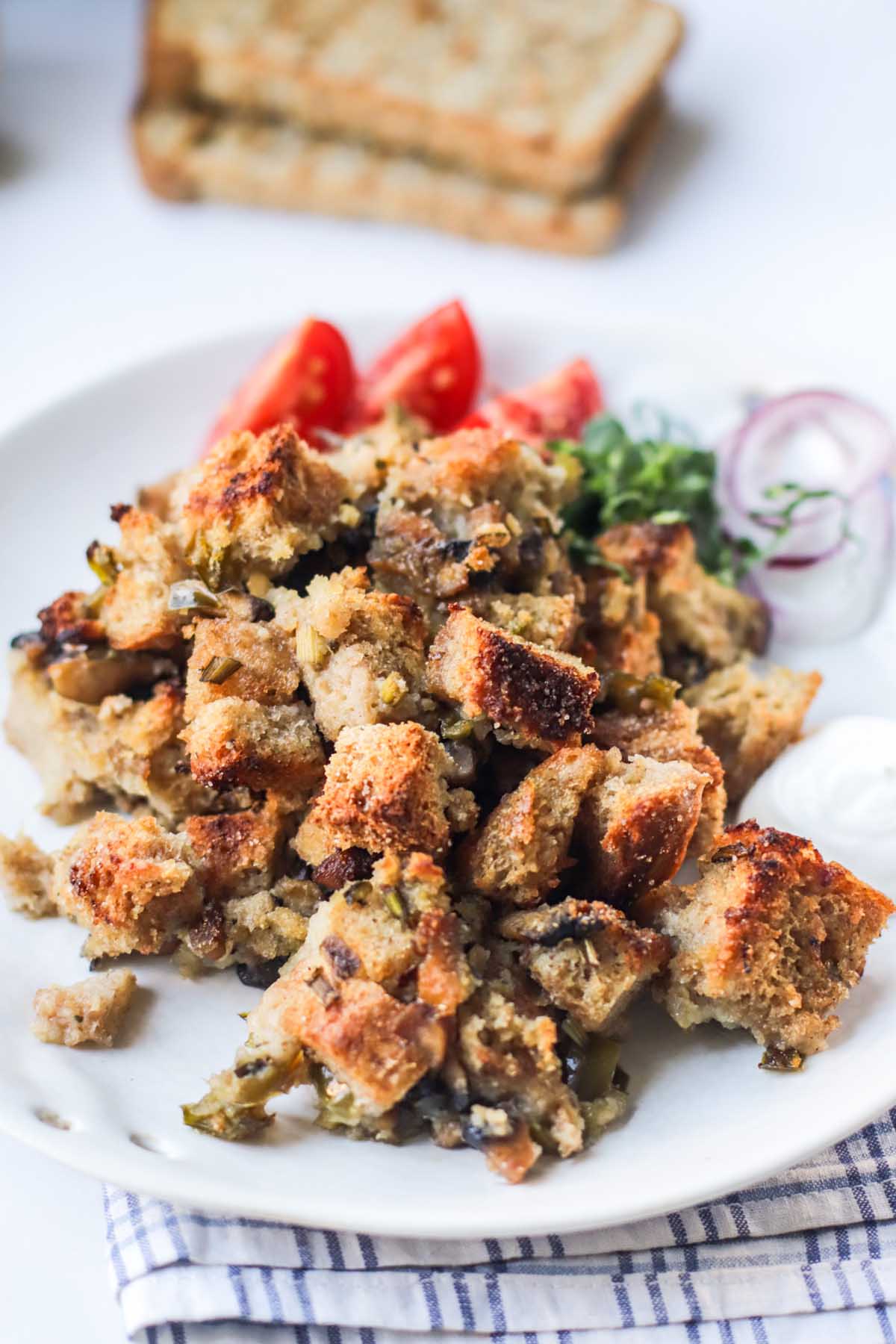 Stuffing on a white plate set on a kitchen towel.