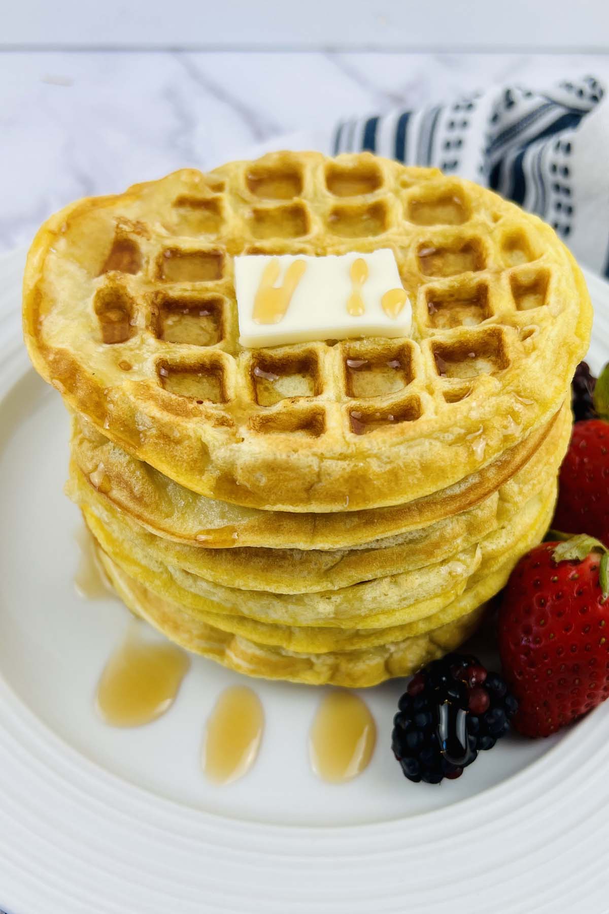 A stack of waffles on a white plate.