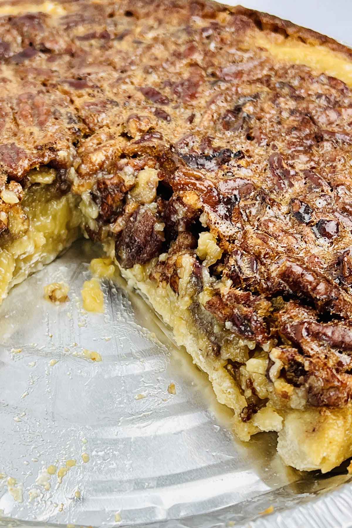 A slice taken out of a pecan pie.