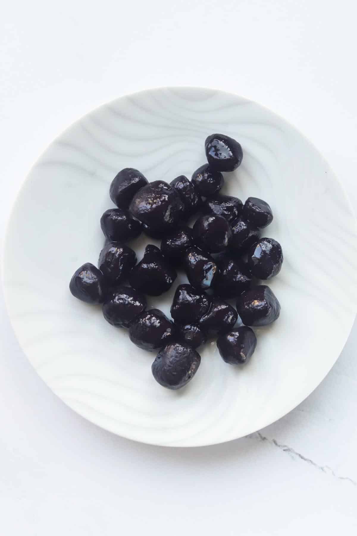 Black tapioca pearls on a white plate.