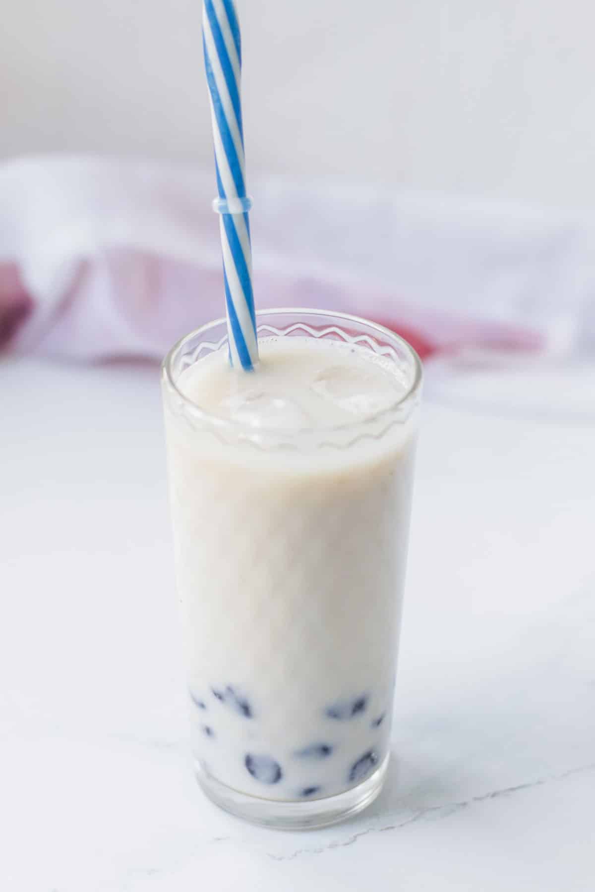 Bubble tea in a glass with a blue straw.