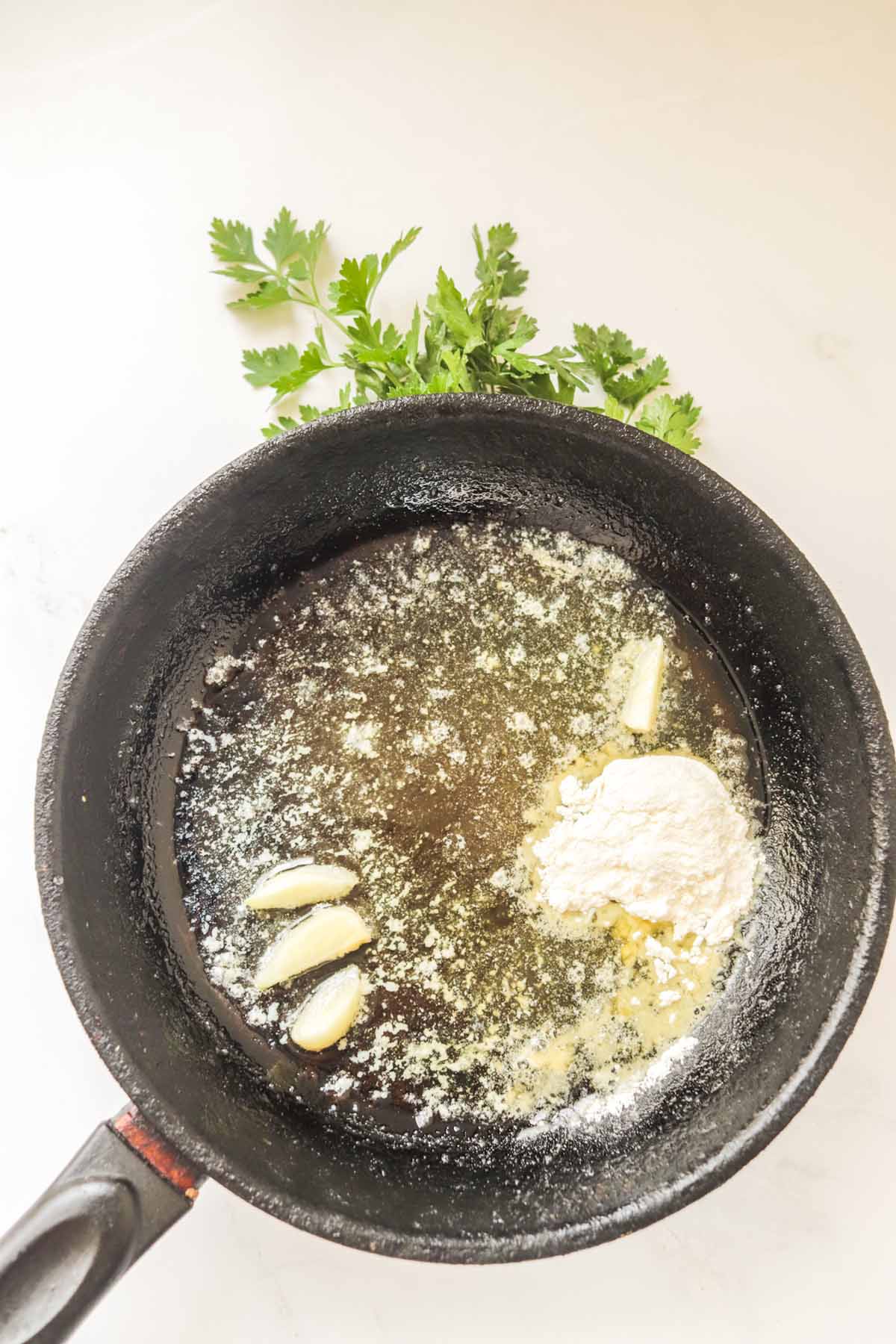 Oil, garlic and flour added to a skillet.