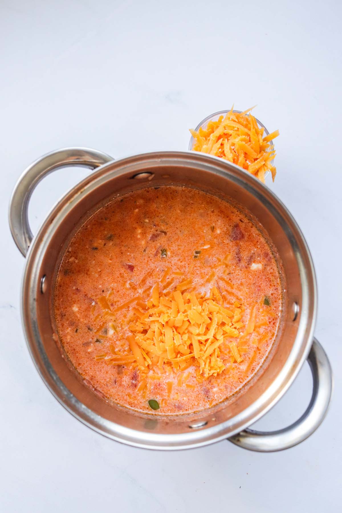 Queso in a pot with shredded cheese on top.