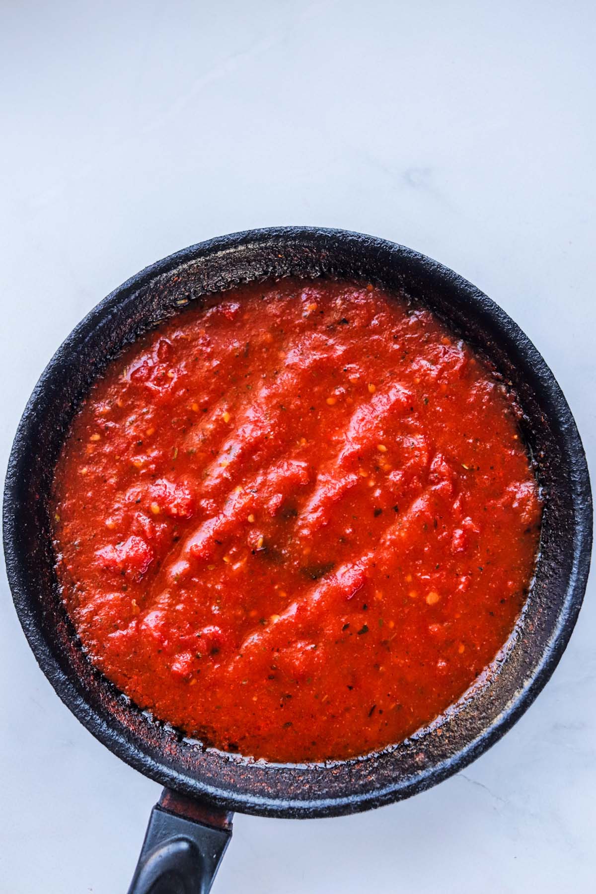 Cooked pizza sauce in a skillet.