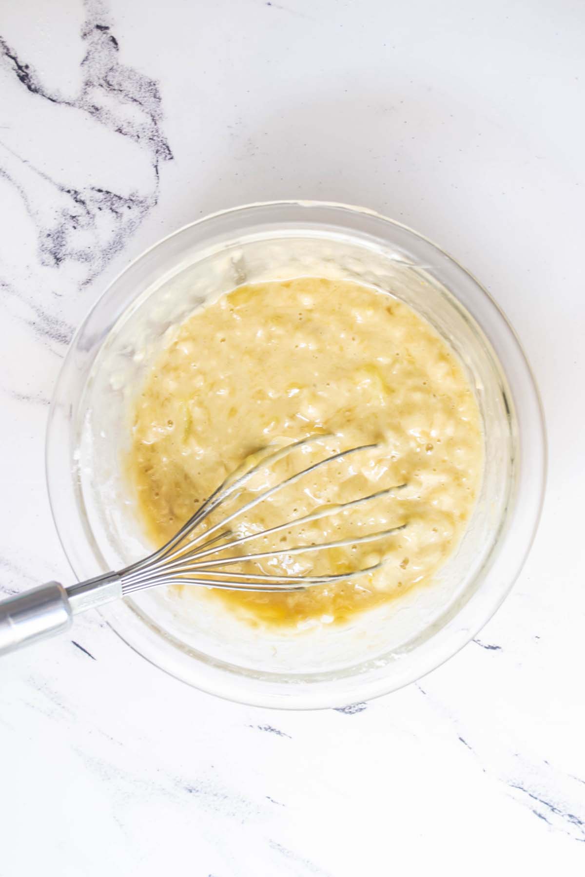 Banana bread batter whisked together in a mixing bowl.