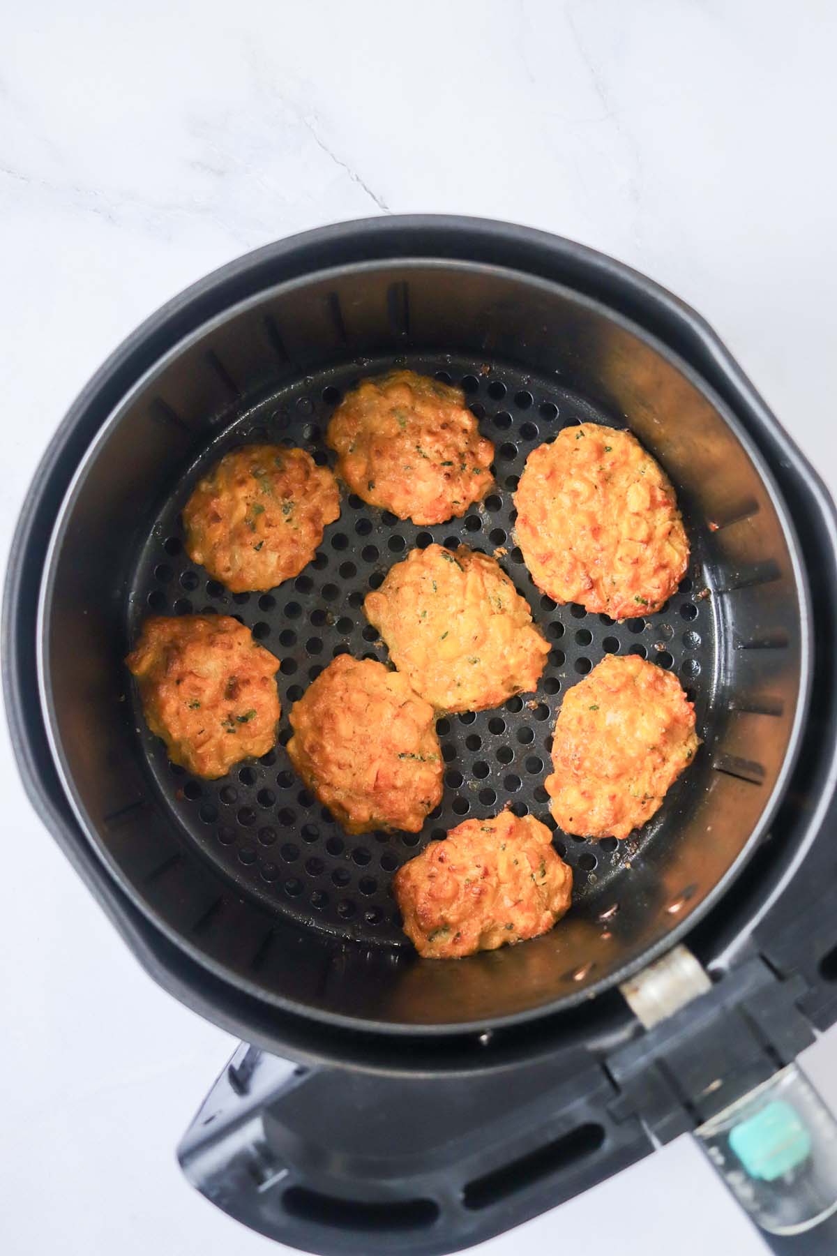 Cooked corn fritters in the air fryer basket.