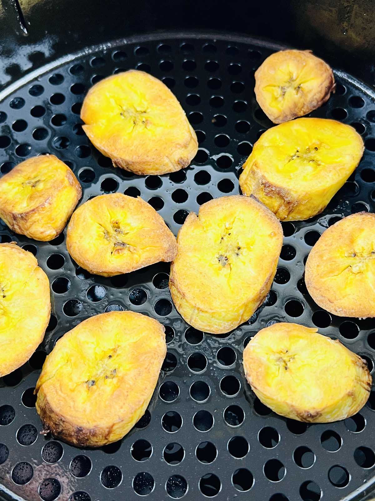 Cooked plantain slices in the air fryer basket.