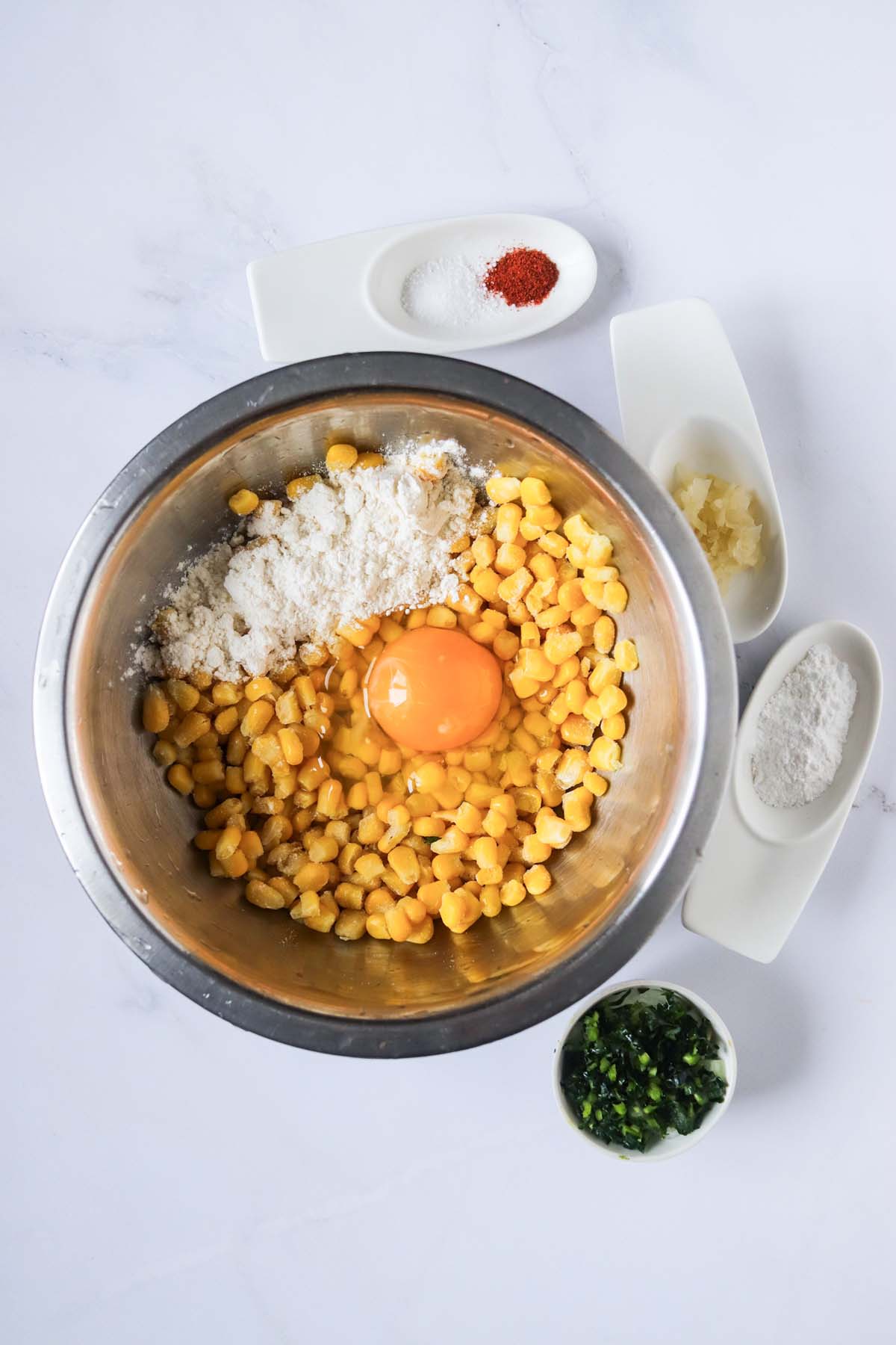 Corn kernels, egg and baking mix in a mixing bowl.