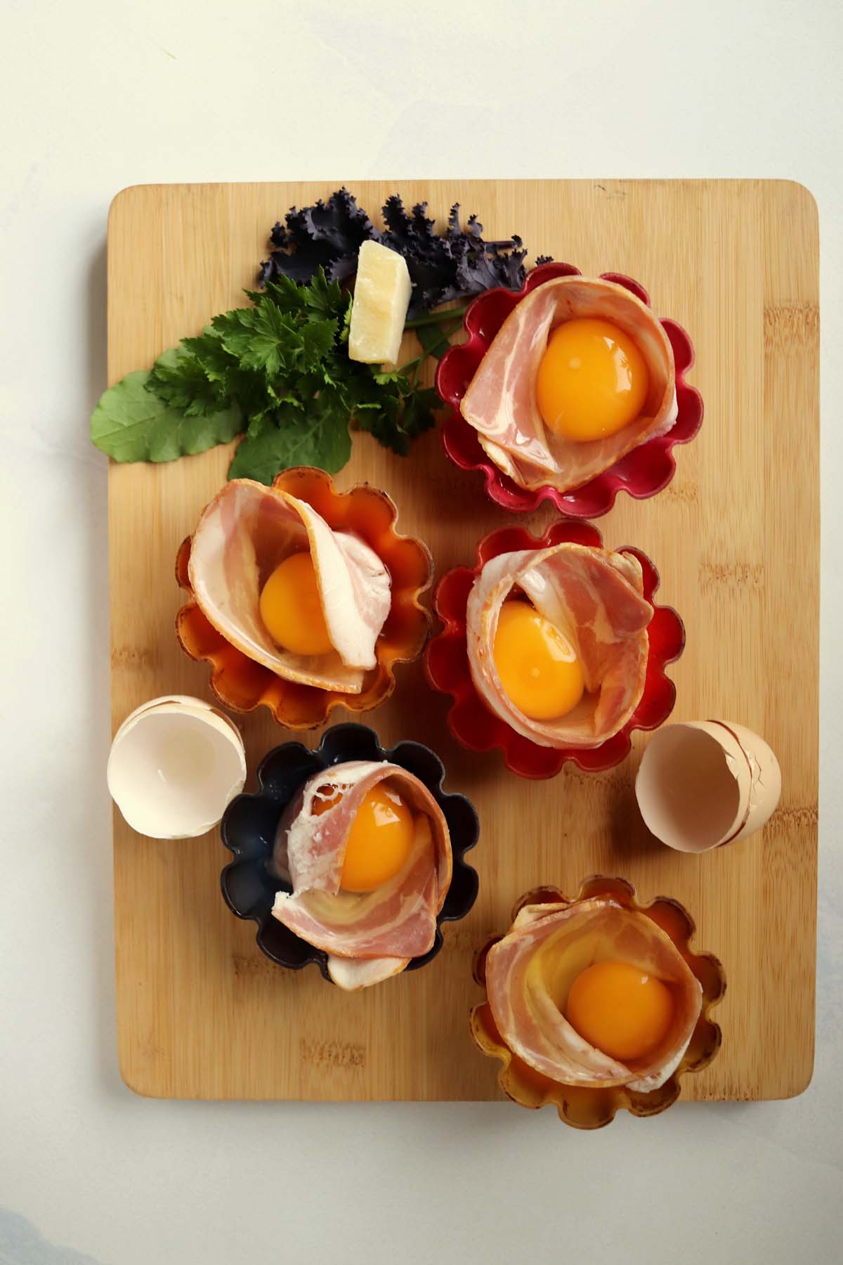 Raw eggs in the middle of the strips of bacon in a silicone liner.