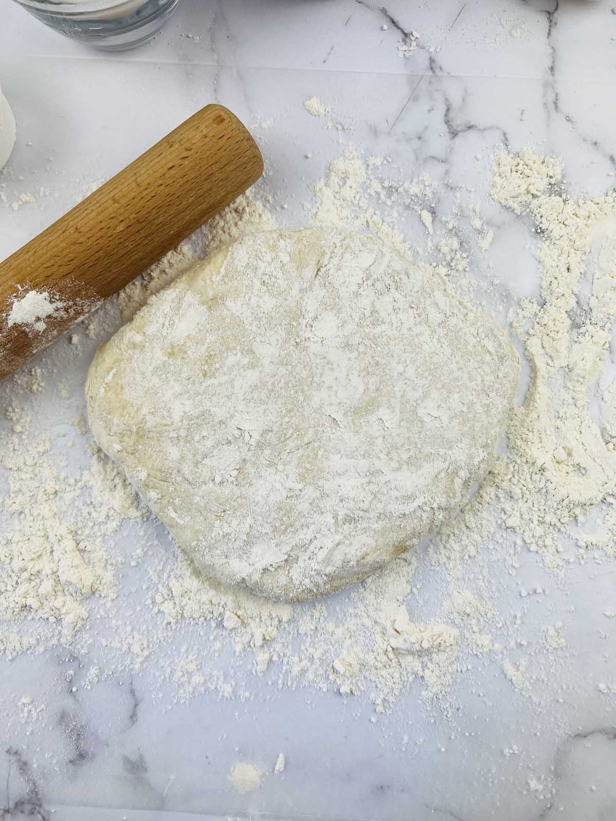 The ball of dough floured with a rolling pin.