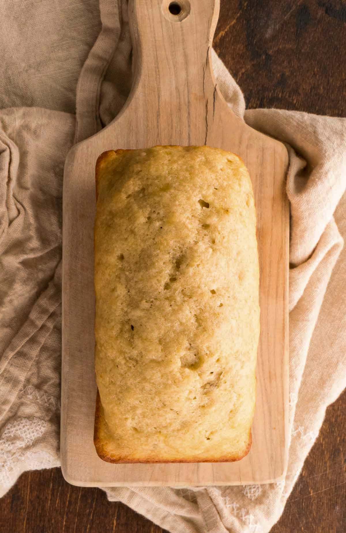 A whole loaf of banana bread on a cutting board.