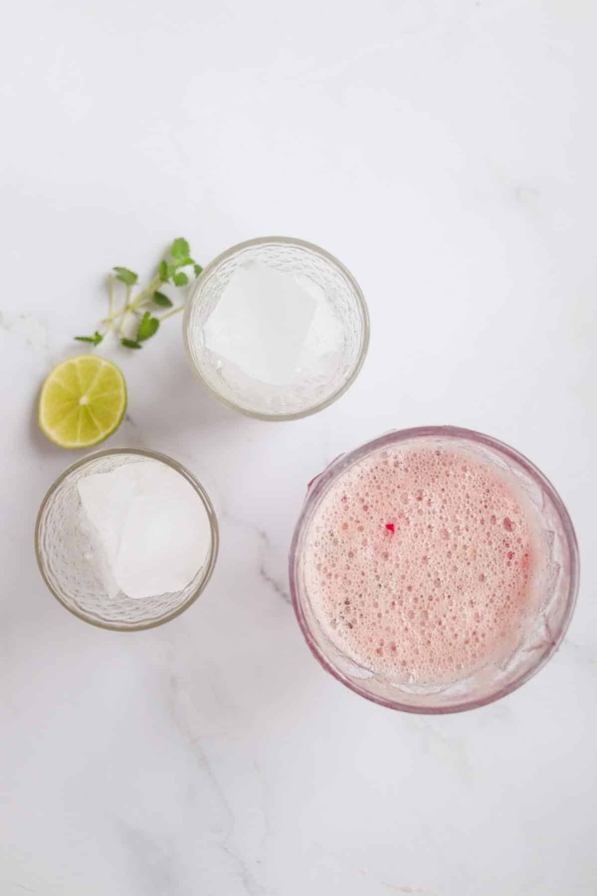 Dragon fruit drink next to glasses of ice.