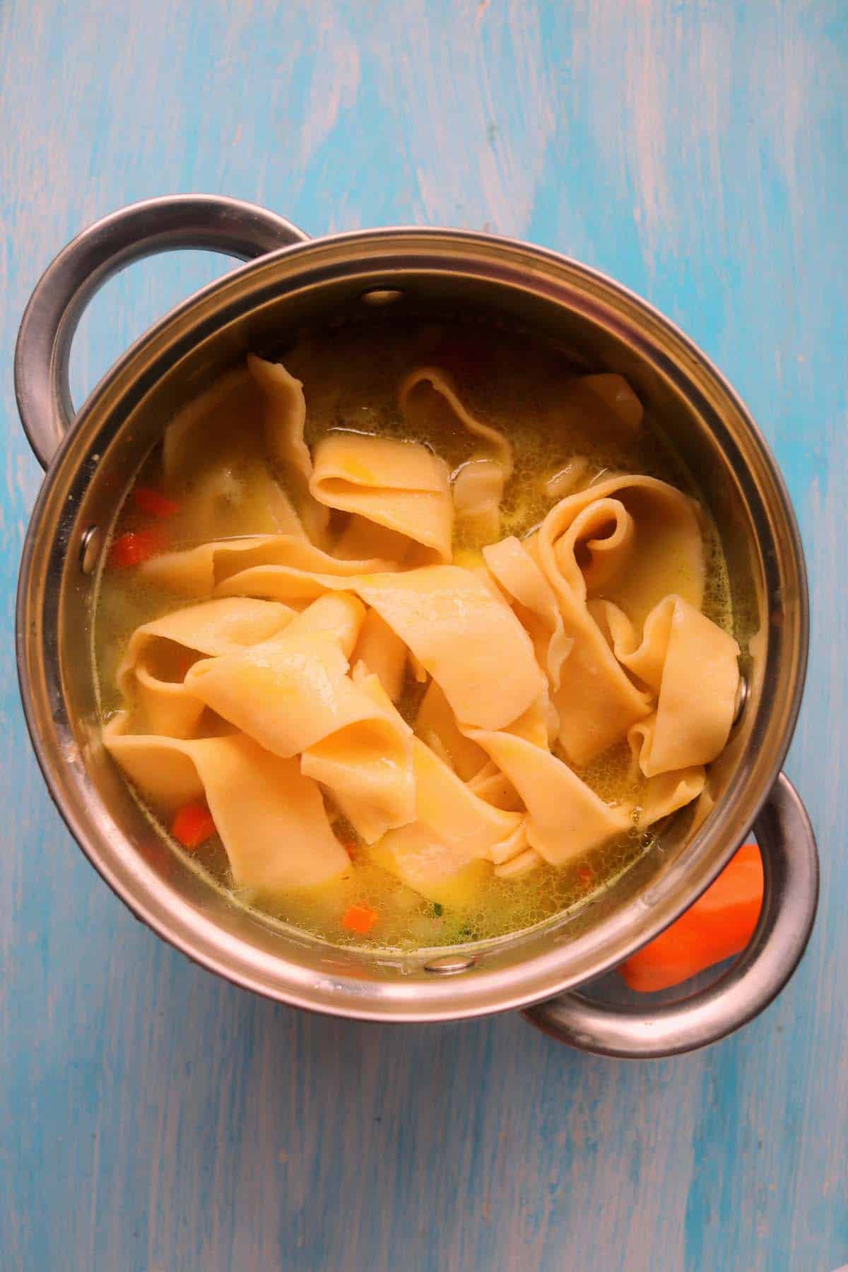 Egg noodles in the pot of chicken soup.