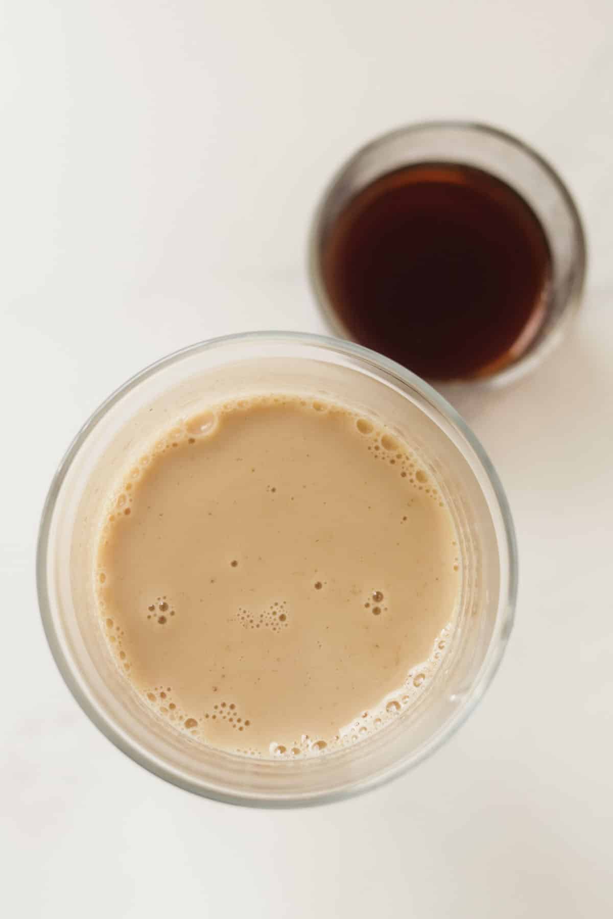 Chai latte in a glass next to the black tea.