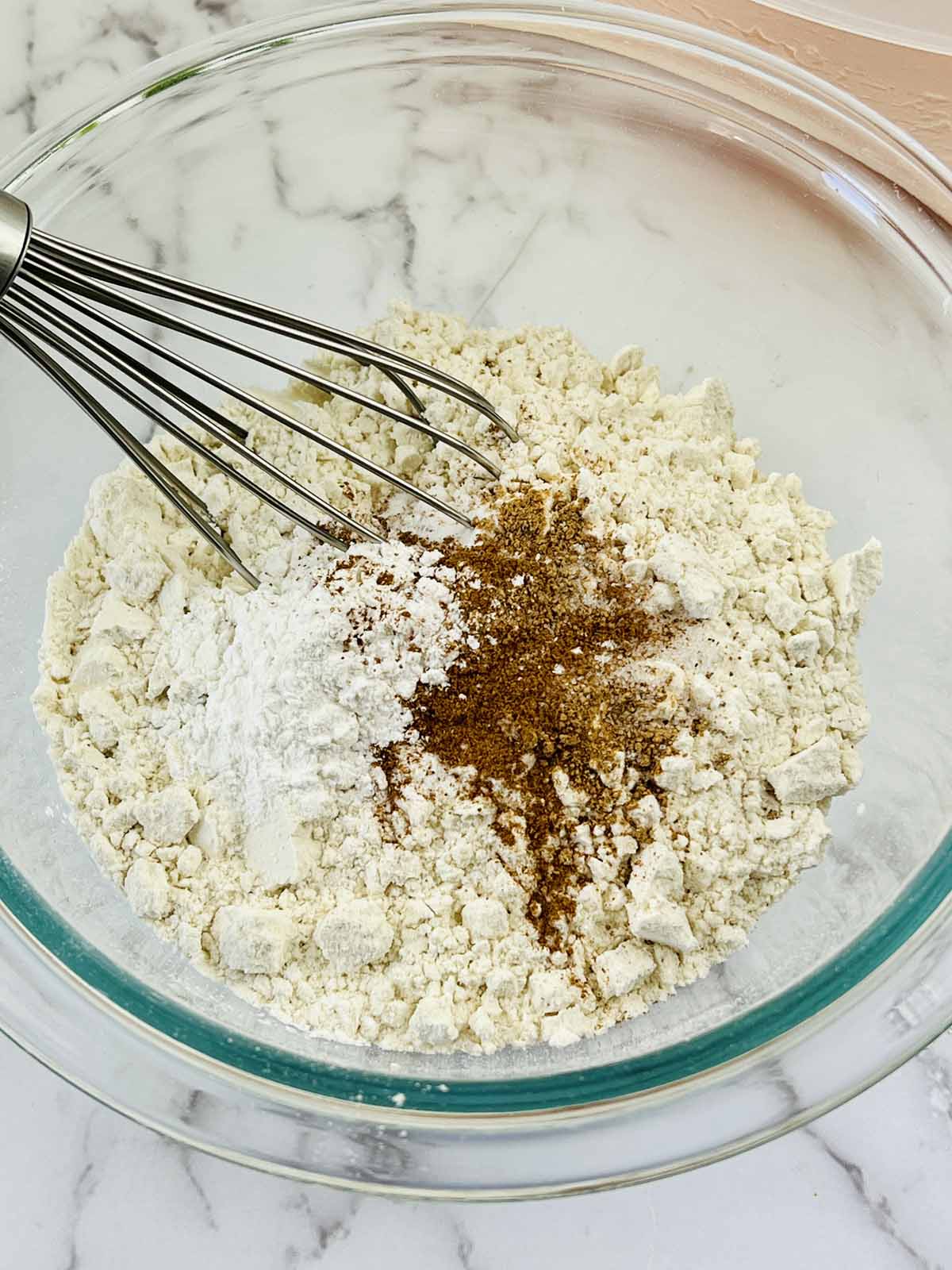 The dry ingredients in a mixing bowl with a whisk.
