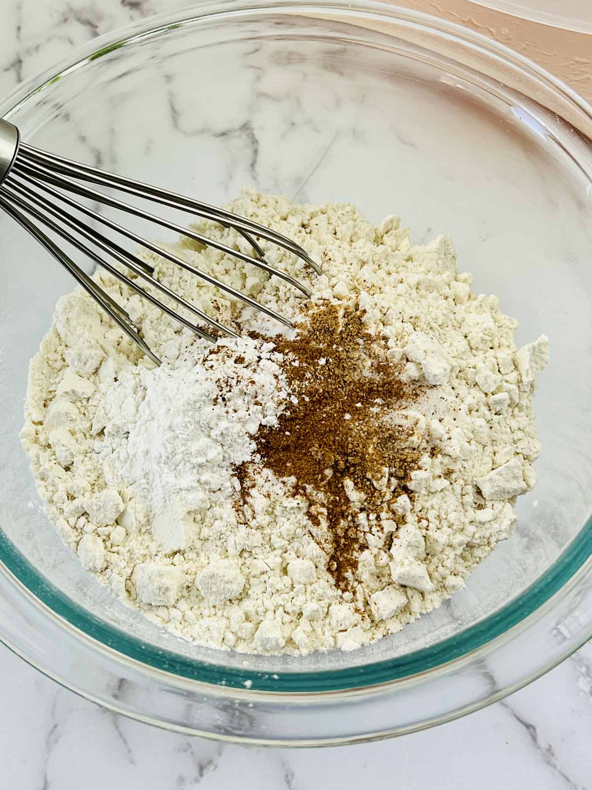 The dry ingredients in a mixing bowl with a whisk.
