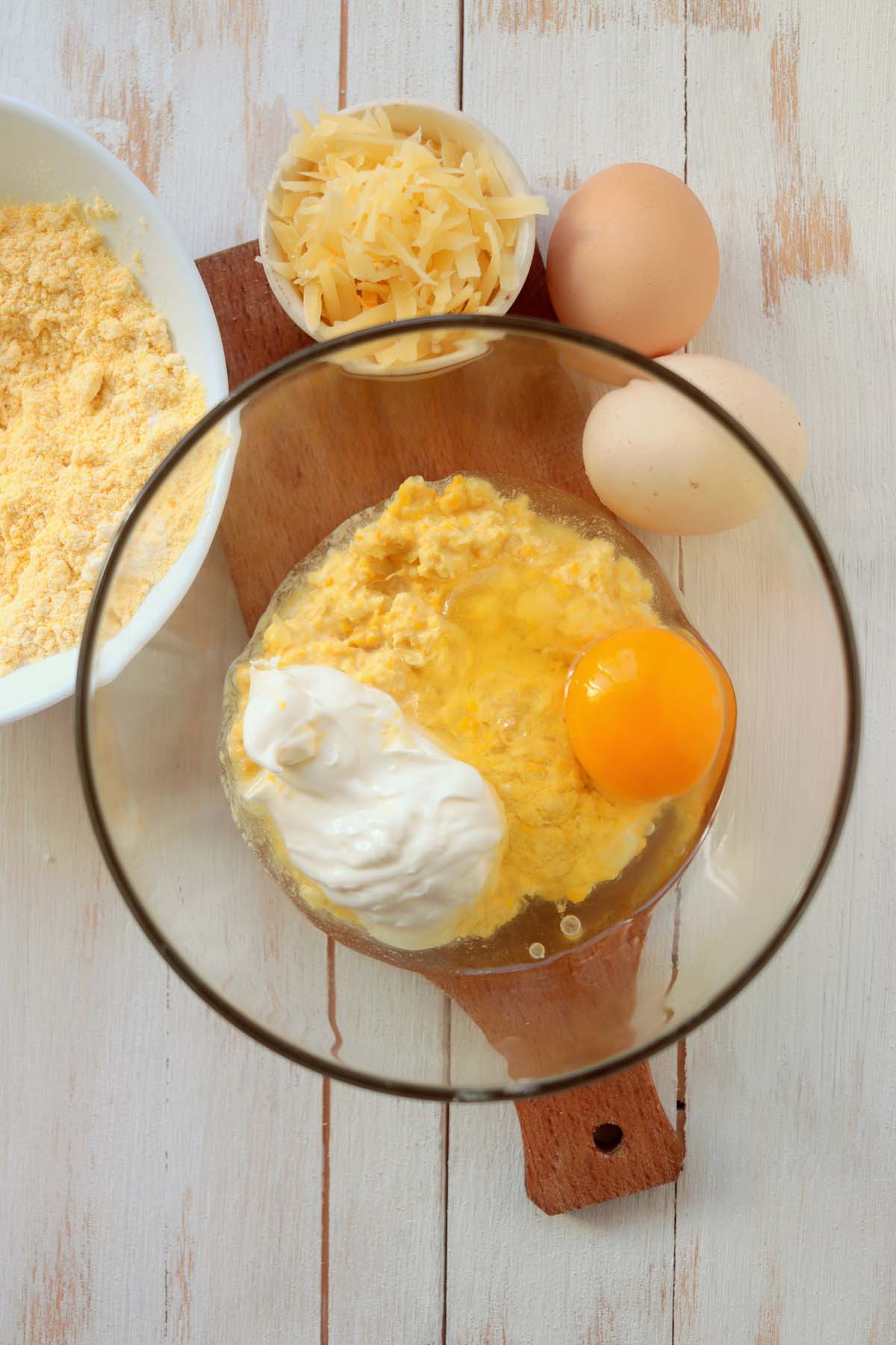 Creamed corn, sour cream and an egg in a bowl.
