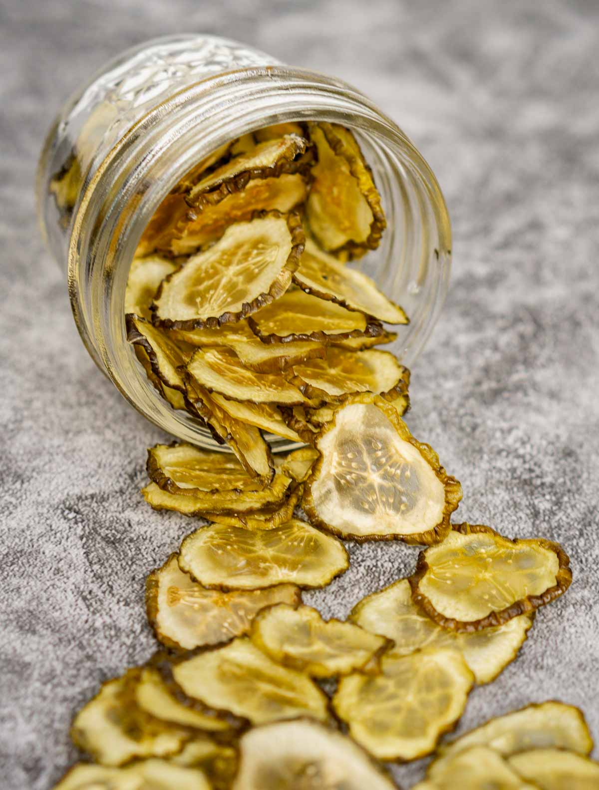 Pickle chips spilled out on the counter from their glass jar.