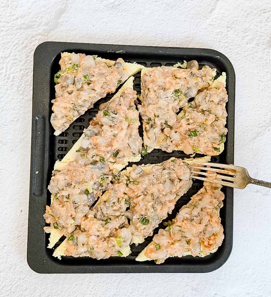 Adding shrimp paste to bread to make shrimp toast